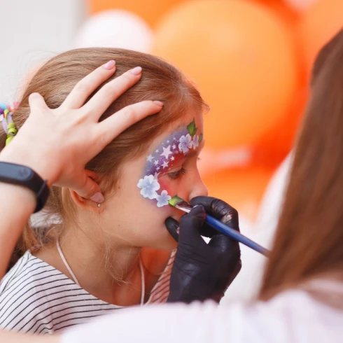 Girl getting her face painted with a floral butterfly design during a children's event in Zurich