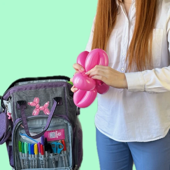Balloon artist holding a pink balloon figure and professional kit