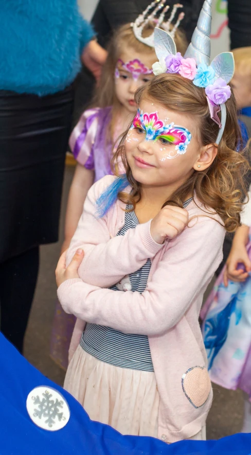 Girl with unicorn headband and colorful butterfly face painting at a party
